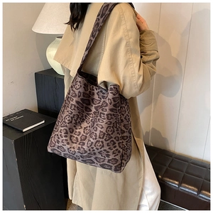 Chic leopard print tote bag styled on a model in a warm indoor setting with broad strap