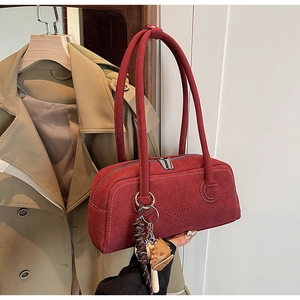 Detail of red faux suede underarm bag with unique baseball glove charm and zip closure