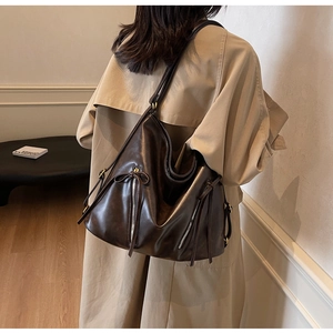 Detail view of large dark brown leather tote bag with vertical zippers and bow details