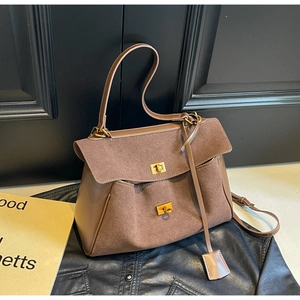 Close-up of brown suede and leather tote with gold metal twist locks on vintage wood