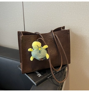Close-up of dark brown tote bag with wrinkled texture and cute turtle keychain charm