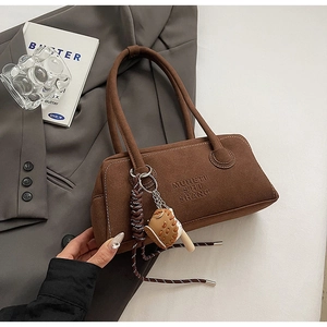 Detail of dark brown suede shoulder bag with MUHETI SHI SHANG logo and baseball glove charm