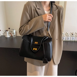 Detail of vintage black leather tote bag with gold swivel lock and adjustable shoulder strap