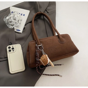 Detail of brown suede shoulder bag with MUHETU embossing and baseball glove pendant