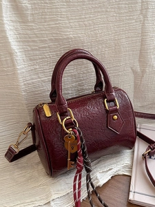 Elegant burgundy Boston handbag with gold hardware and stylish key lock pendant