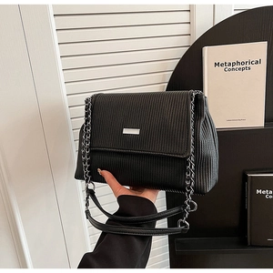 Détail du sac cabas plissé noir avec bandoulière en chaîne argentée et logo métal