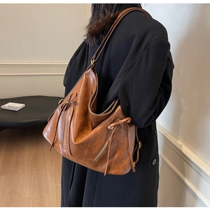 Detail view of brown vintage leather tote with bow drawstring and gold metal zipper