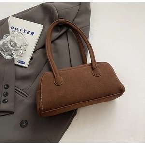 Detailed shot of a caramel suede underarm bag with contrast stitching on a grey blazer