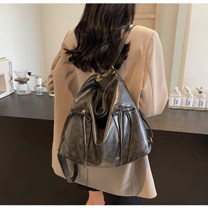 Detail of vintage black faux leather backpack featuring side zipper and bow decoration