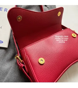 Detailed close-up of red lychee leather texture and gold magnetic buckle on handbag