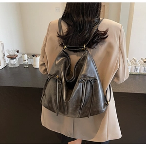 Macro detail of charcoal grey faux leather backpack with vertical zippers and bow tie decor