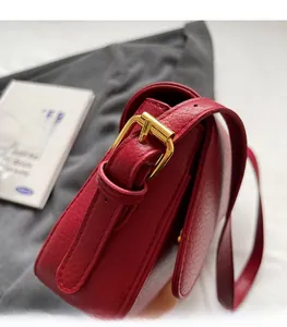 Detail of red pebbled leather shoulder bag with polished gold-tone metal hardware