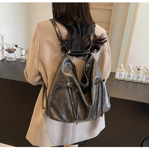 Detail of vintage black leather backpack with matte finish and long strap accents