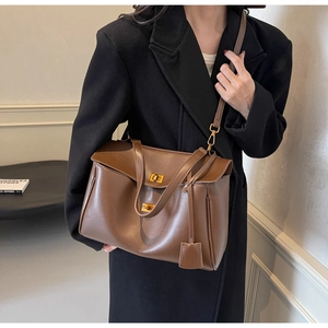 Detail of a vintage dark brown leather tote bag with a gold twist lock and side gussets