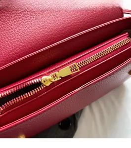 Detail of smooth gold zipper on dark red lychee grain leather handbag interior