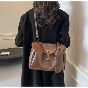 Brown vintage leather tote bag shown with gold turn-lock closure and adjustable strap