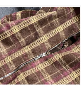 Détail du motif à carreaux classique et fermeture éclair en métal sur un sac marron