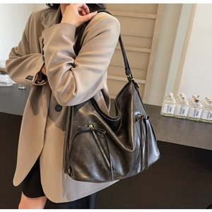 Detail of vintage black leather tote bag with side zipper pocket and tied ribbon bow