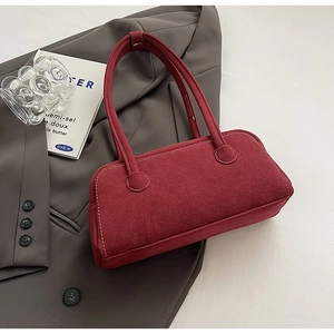 Detail of burgundy suede underarm bag with contrast stitching on a grey suit jacket