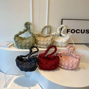 Close-up of quilted puff cloud bags in various colors on a white display stand