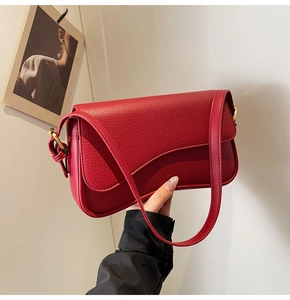 Detailed close-up of red lychee grain leather handbag with elegant golden hardware