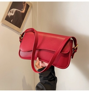 Close-up of red lychee pattern leather shoulder bag with gold metal buckle detail