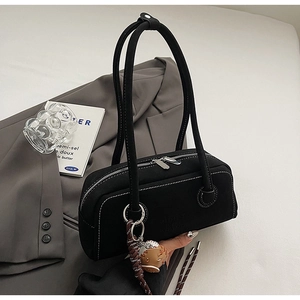 Detail of black canvas shoulder bag featuring white contrast stitching and baseball pendant