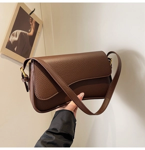 Detail of dark brown lychee grain leather shoulder bag with golden hardware and buckle