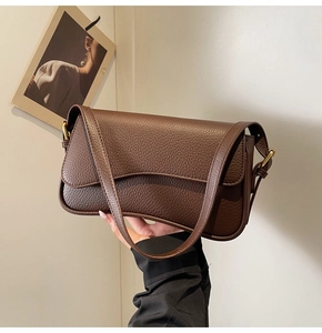Detail of dark brown lychee-patterned leather shoulder bag with gold hardware buckle