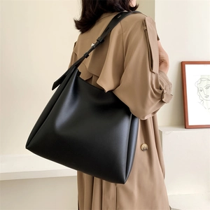 Detail view of large black tote bag on model showing size and adjustable shoulder strap