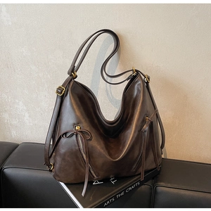 Detail of dark brown hobo tote with dual zipper pockets and bow tie leather tassels