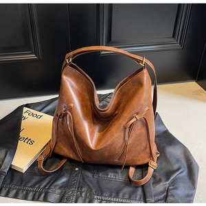Close-up of vintage brown PU leather backpack showing decorative zippers and brass hardware