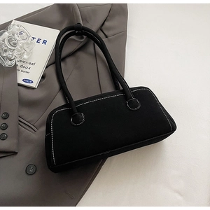 Detailed view of black underarm bag featuring contrasting white stitching and smooth texture