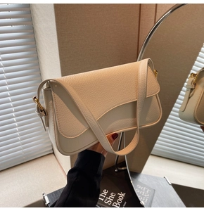 Detail of cream lychee leather shoulder bag with gold hardware and saddle flap design