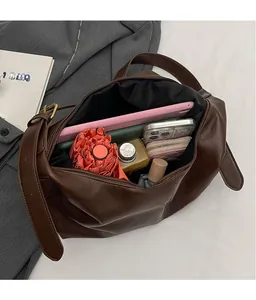 Détail intérieur d'un grand sac fourre-tout en cuir PU marron rempli d'objets du quotidien
