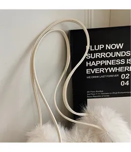 Gros plan du sac seau en peluche crème avec une longue bandoulière fine en similicuir