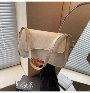 Detail of minimalist beige lychee leather shoulder bag with golden hardware and flap design