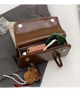Vue de dessus de l'intérieur du sac porté épaule en similicuir marron avec ours en peluche