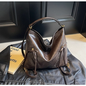 Close-up of vintage dark brown faux leather backpack with metallic zippers on black leather