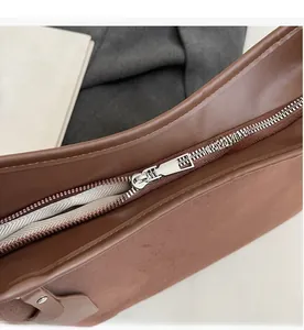 Detailed close-up of smooth silver metal zipper on vintage brown leather crossbody bag