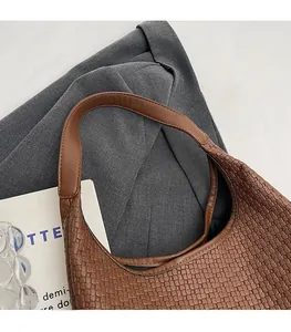 Gros plan sur la texture en cuir tressé marron et la bandoulière lisse du sac hobo chic