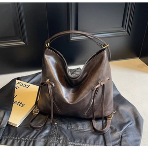 Detail of dark brown vintage leather hobo bag with zip accents on black leather jacket