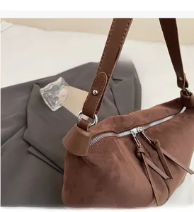 Détail d'un sac porté épaule en daim marron avec ferrures argentées et double fermeture