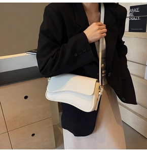 Detail of white lychee leather shoulder bag with irregular flap on a female model