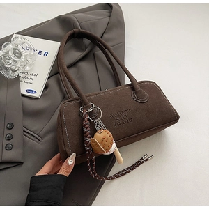 Detail of dark brown matte suede shoulder bag with unique baseball themed charms