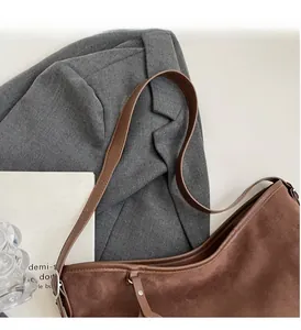 Detailed view of a brown suede hobo bag with leather strap next to a grey blazer
