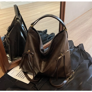 Detail of vintage large capacity dark brown soft leather backpack with bow tassels