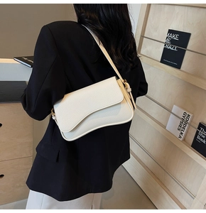 Detail of white litchi pattern leather shoulder bag with gold buckle on a model