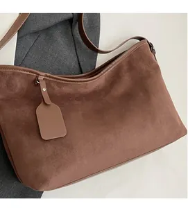 Detail of soft brown suede shoulder bag with high capacity and smooth leather piping