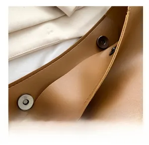 Close-up of dual magnetic snap closures on the brown leather tote bag interior